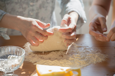 Women cooking pizza at home. Two unrecognizable women kneading doughの写真素材