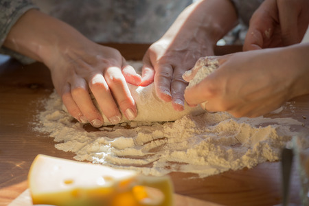 Women cooking pizza at home. Two unrecognizable women kneading doughの写真素材