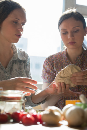 Women cooking pizza at home. Two women kneading doughの写真素材