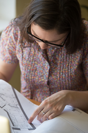Woman working at home with laptop and architecture planの写真素材