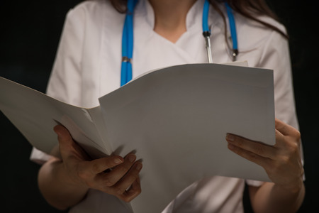 Unrecognizable female doctor reading medical recordの写真素材
