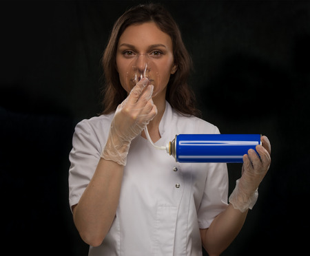Female doctor holding can with oxygen and breathing through the maskの写真素材