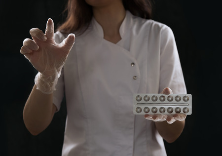 Doctor wearing gloves working with virtual screen and holding tabletsの写真素材