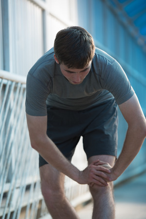 Attractive fit young man stretching before exercise, sunrise early morning backlit. Shallow depth of fieldの写真素材