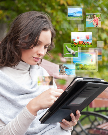 Portrait of young happy woman sharing her photo and video files in social media resources using her modern tablet computerの写真素材