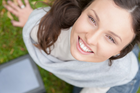 Young woman using tablet computer outdoor sitting on grass. Top viewの写真素材