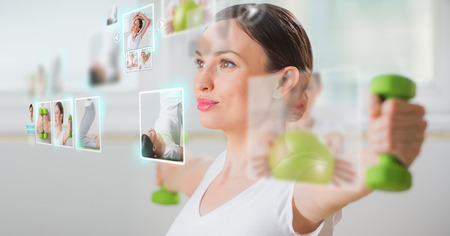 Sporty woman working out using modern virtual interface. Online fitness trainer conceptの写真素材