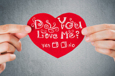 Do you love me? Valentine's day background. Closeup of female hands holding red heart with signの写真素材
