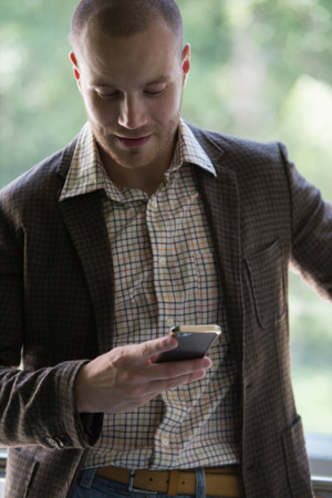 Happy young businessman reading text message on smartphoneの写真素材