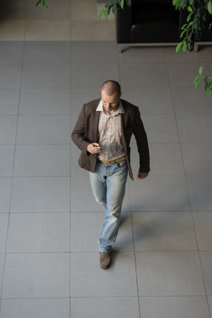 Attractive businessman using his cell phone in office building lobby. Top viewの写真素材
