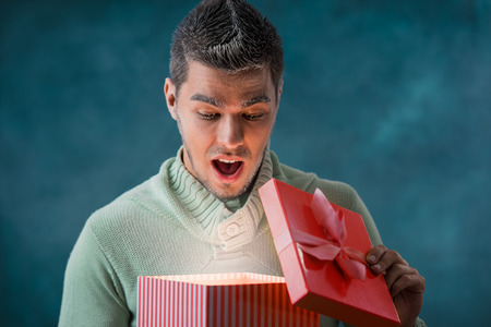 Excited man opening big gift box outdoors at winter. Frost on his faceの写真素材