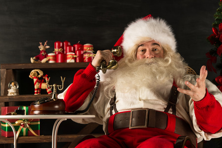 Portrait of emotional Santa Claus calling phone at homeの写真素材