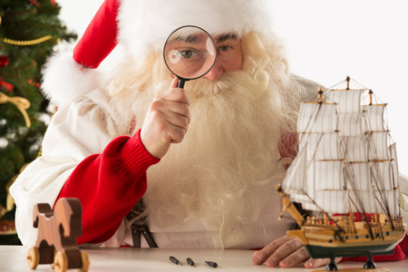 Santa Claus making toys. Looking at camera through the magnifying glass zoomの写真素材