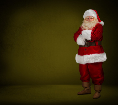 Photo of happy Santa Claus looking at camera on yellow background. Full length portraitの写真素材