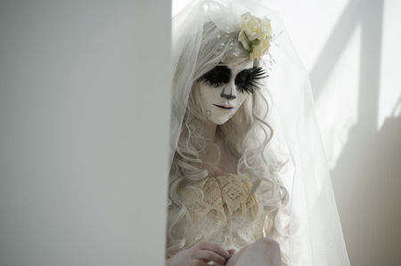 Halloween witch. Beautiful woman wearing santa muerte mask and wedding dressの写真素材