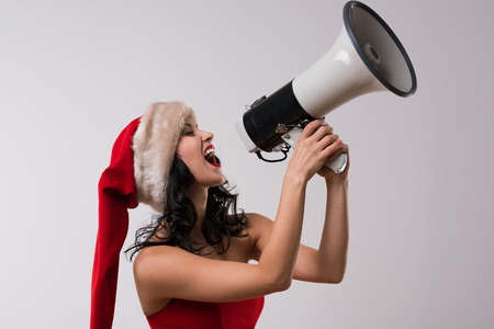 Christmas woman with megaphone against a white background. Wearing Santa Claus red hat and dressの写真素材