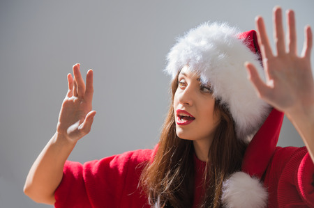 Christmas woman wearing Santa Claus hat working with virtual interfaceの写真素材
