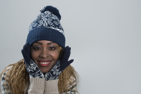 Portrait of african woman on gray background wearing woolen accessoriesの写真素材