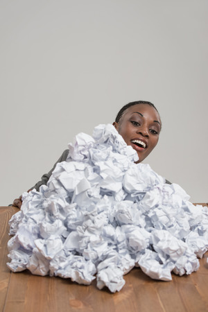 African business woman with crumpled pile of papers at workplace at officeの写真素材