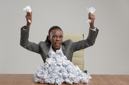 African business woman is tired of work . Sitting in front of crumpled paper pile . Unhappy with cvの写真素材