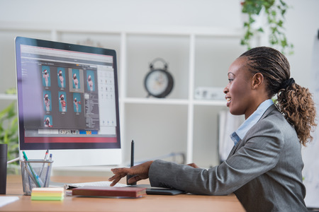 Portrait of pretty african female designer working with graphic tablet and computer at officeの写真素材