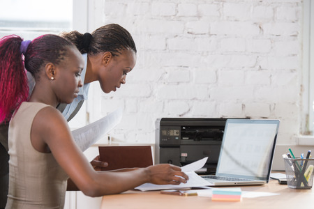 Young african business women in office working together on laptopの写真素材