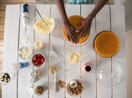 Beautiful young african woman cooking cake at kitchen. Top viewの写真素材