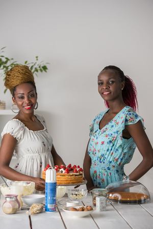 Young african women at the kitchen cooking cake with strawberryの写真素材