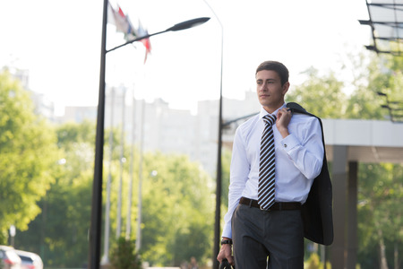 Portrait of a handsome businessman walking on the street near office buildingの写真素材