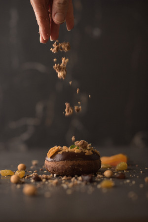 Chocolate Donut sprinkled with crumbs on dark stone backgroundの写真素材