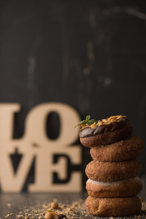 Stack of Donuts with crumbs, nuts and love sign on dark stone backgroundの写真素材