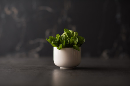 Bunch of fresh mint in cup on rustic stone backgroundの写真素材