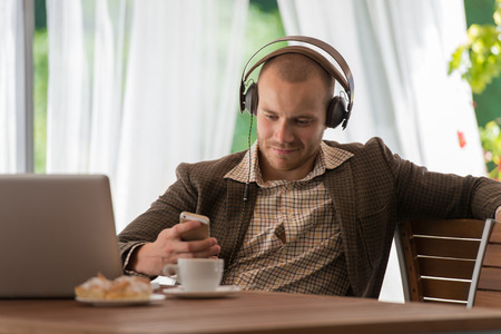 Business man resting at cafe and listening music using vintage headphonesの写真素材