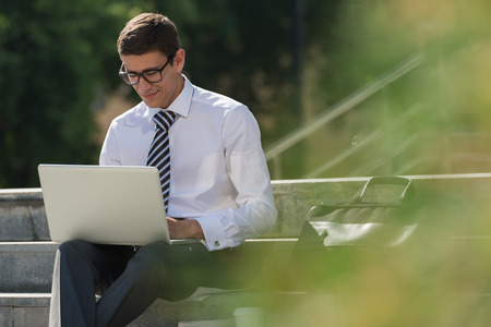 Man with laptop at summer park on bright dayの写真素材