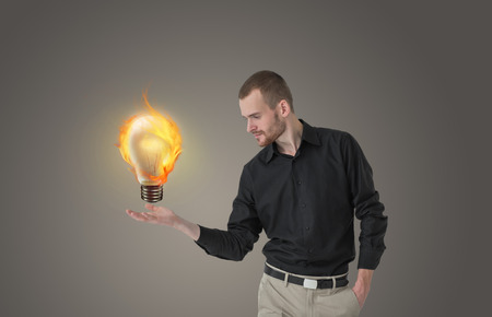 Beautiful business man with idea light bulb above head on gray background