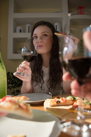 Romantic couple dating at home. Drinking red wine, eating fresh homemade pizza. Photo from the first personの写真素材
