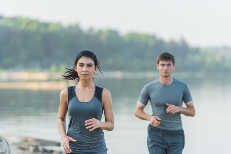 Cheerful Hispanic Caucasian couple running on beach at morningの写真素材