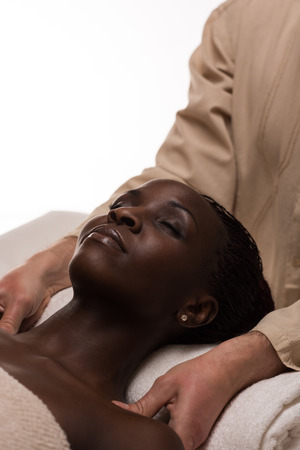 Beautiful young african woman enjoys shoulders massage in a luxury spa resortの写真素材