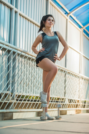 Woman posing with dumbbells outdoors in urban placeの写真素材