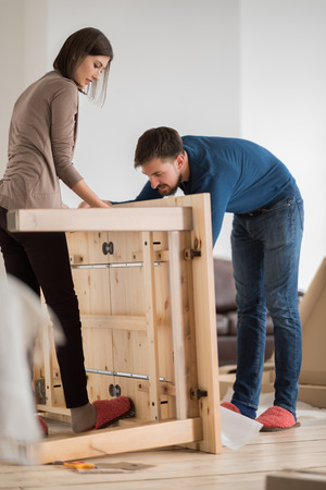 Happy young couple putting together self assembly furniture as they move into their new house.の写真素材