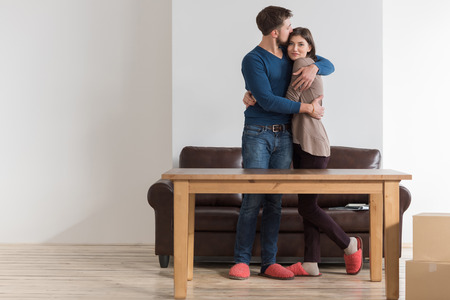 Side view of happy young couple embracing in living room of new homeの写真素材