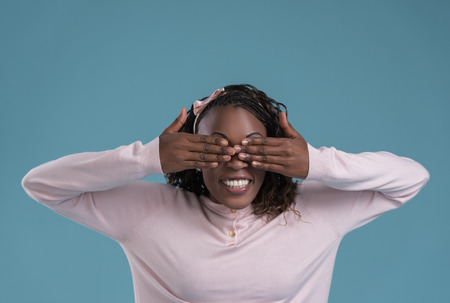 Portrait of cute african woman posing - hiding eyes with handsの写真素材