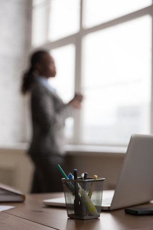 Candid image of a businesswoman drinking coffee while working at office. Selective focus.の写真素材