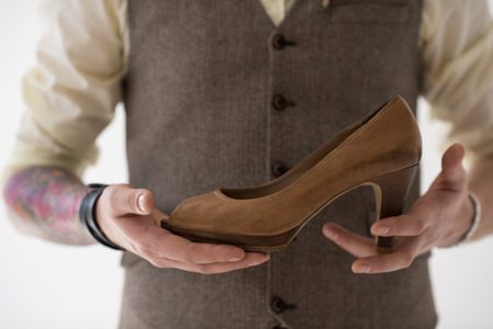 Closeup portrait of modern groom holding shoe of his bride