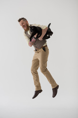 Full length portrait of modern groom jumping with his catの写真素材