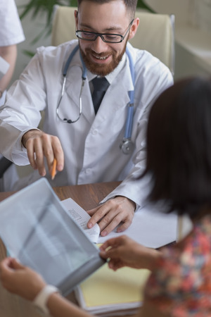 Confident practitioner consulting woman in hospital. Explaining results of chest x-ray scanの写真素材