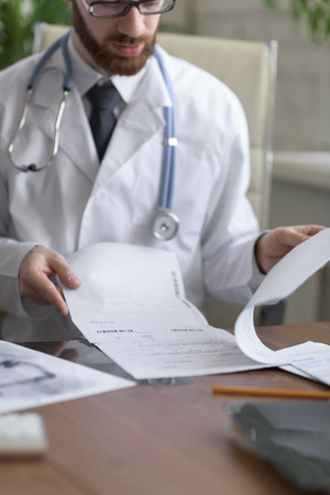 Doctor working with test results of his patient at his officeの写真素材