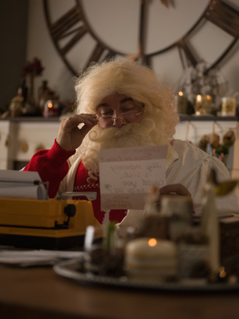Santa Claus Working at Home. Reading and Writing letters for Children on Typewriterの写真素材