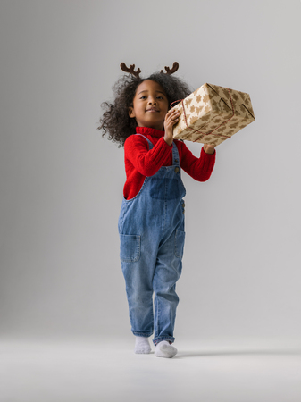 African little girl with Christmas Gift full length Portrait on plain backgroundの写真素材
