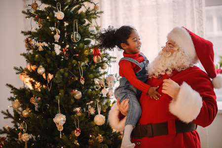 Santa Claus playing with cute african american Child at Homeの写真素材